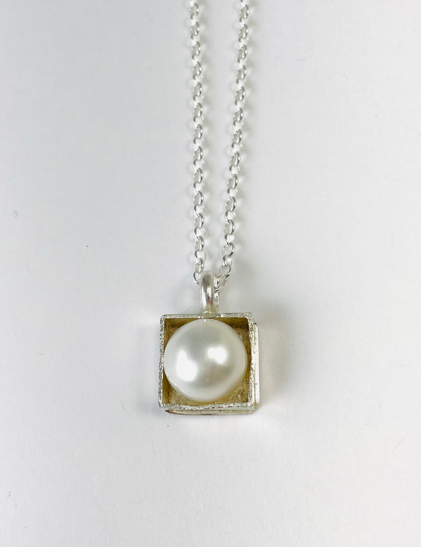 Sterling silver 'pearl in a box' pendant on an 18-inch curb chain.